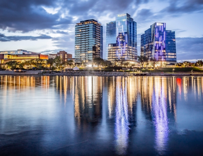 City skyline of Saskatoon at dusk with the buildings reflecting in the water in theforeground