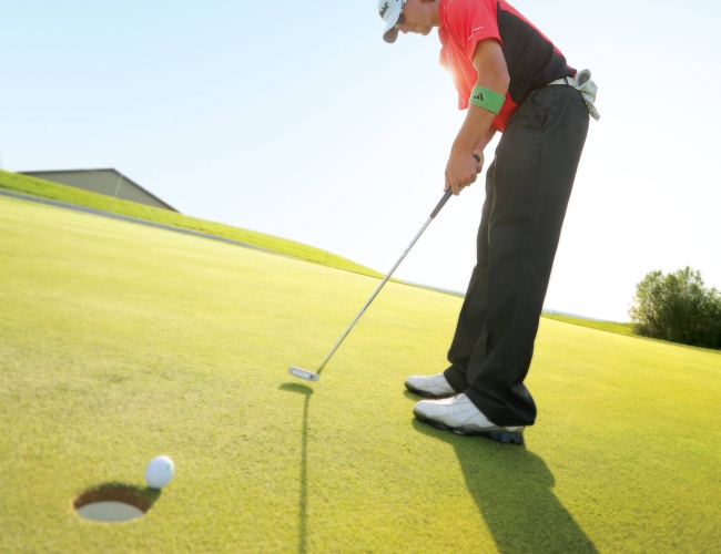 Man putting the ball into the hole on a golf green