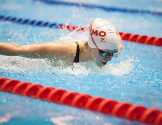 An individual swimming the butterfly stroke and wearing a swimming map and goggles