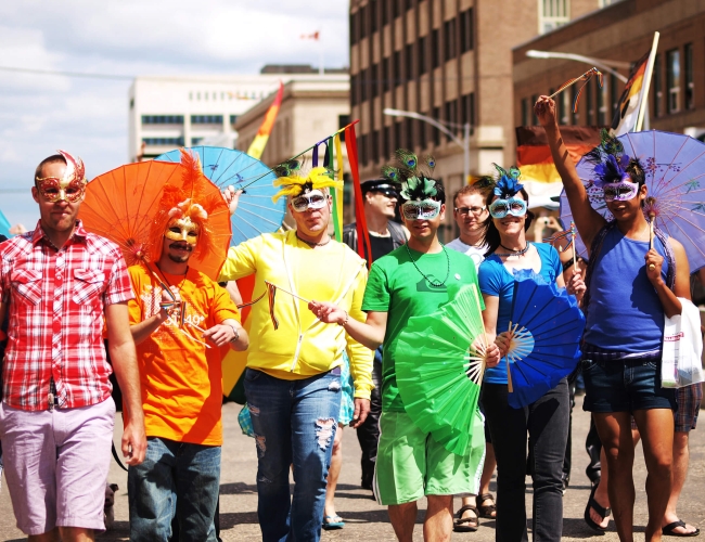 Members of the LGBTQ2S+ community dressed in bright clothing walking in the pride parade