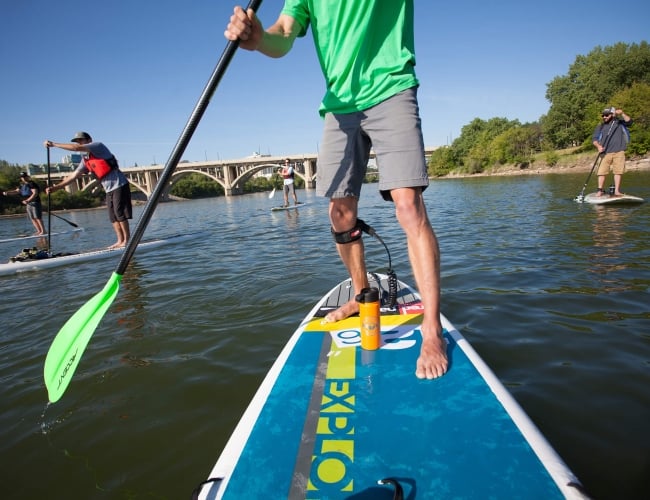 Two friends stand up paddleboarding on open water