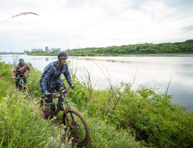Two people cycling on a trail by a river