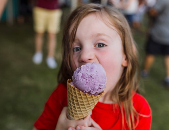 a child eating a purple ice cream cone