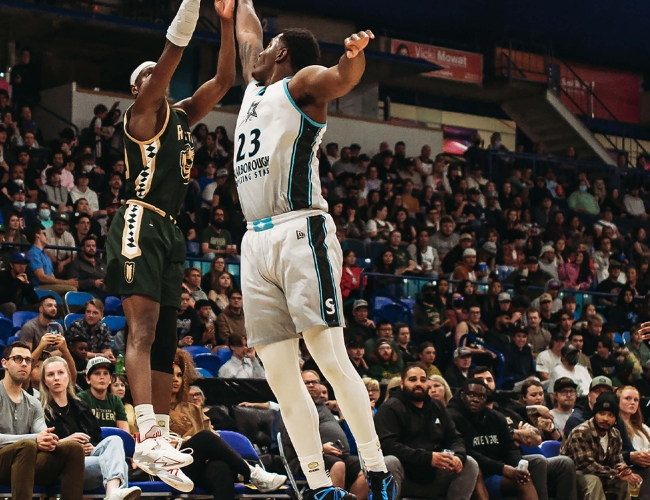 Two men playing basketball, jumping to get the ball