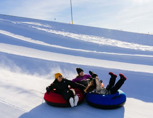 children tubing down a hill in the winter