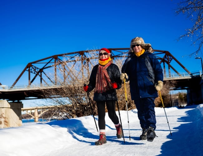 a couple cross country skiing with a bridge in the background