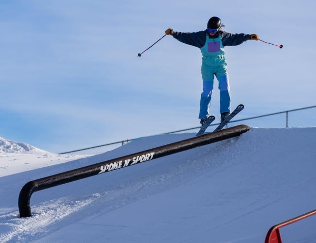 An individual on skis grinding on a pipe