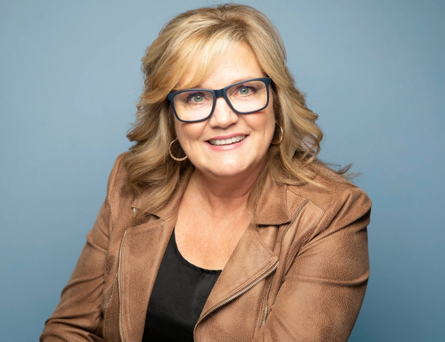 Headshot for Marcy Atchison against a blue background