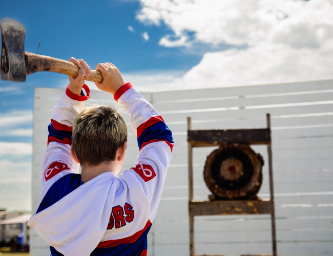 a young man throws an axe at an outdoor target