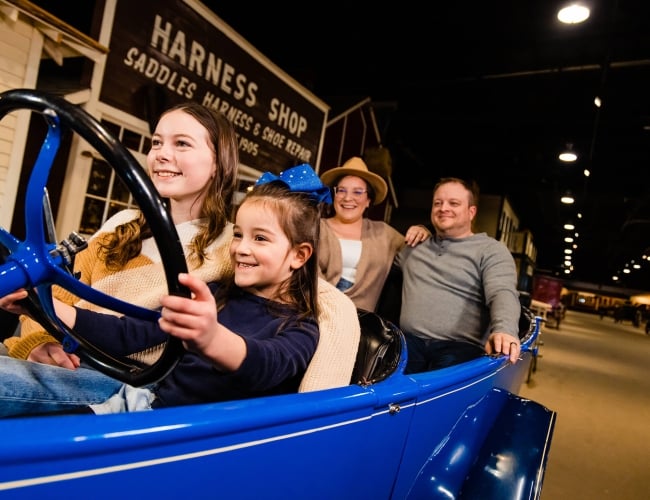 a family pretending to drive a model car in a historic museum