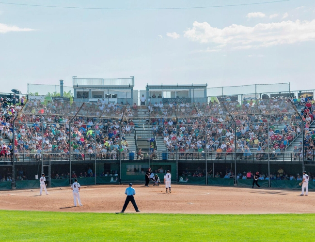 An outdoor baseball game with the stands filled with fans.