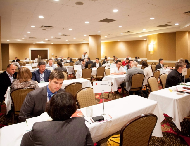 A group of individuals sitting at long tables in a conference setting