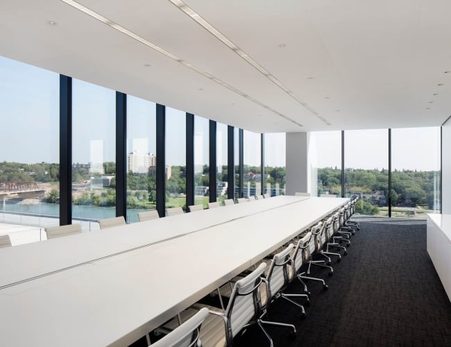 A large boardroom table in a meeting room with a glass wall