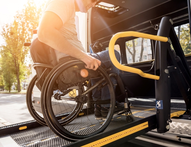 An man in a wheelchair boarding a bus using a chair lift. 