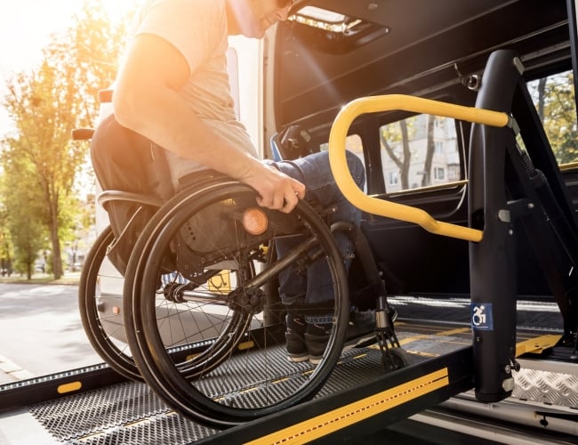 An man in a wheelchair boarding a bus using a chair lift.