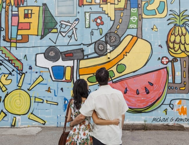 Couple embracing and looking at an outdoor painted wall mural