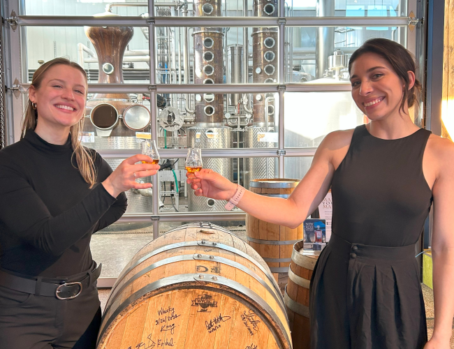 Whisky Glencairn glass filled with whisky with two smiling females celebrating event.