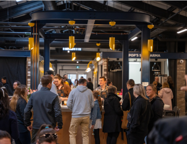 People standing around a bar, waiting to be served drinks