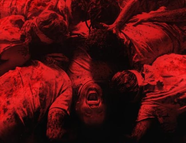 Image from the movie 1978. Shows a group of people piled onto each other and someone screaming with a red filter showing the picture as red and black.