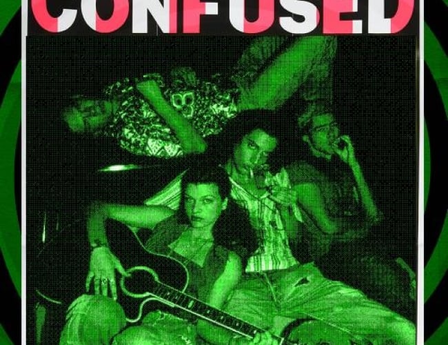 Image from the movie Dazed and Confused. Shows 4 of the actors lounging on a couch, with two smoking, another playing a guitar and the fourth playing at the top of the couch, all looking at the camera. Image is tinted to be green and black, distorting all the other colours.