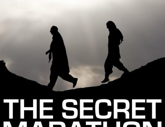 Image of the movie; the secret marathon. Shows two people walking on a hill with the sun shining down on them. 