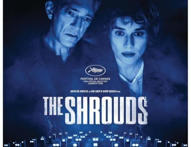 Image from the movie The Shrouds with two of the actors overlooking rectangular graves with lights on them. 