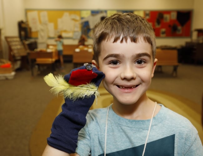 Boy smiling with a homemade sock puppet on his hand