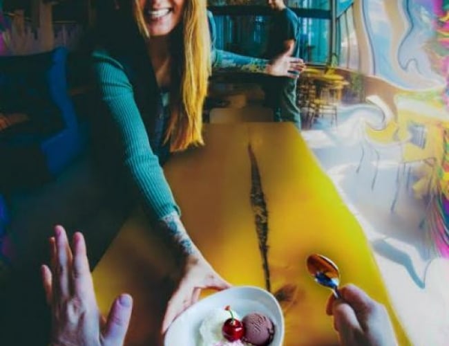Image is a point of view of the viewer being served a bowl of ice cream by Mikhaila Anderson with the viewers hands holding a spoon. The background is a restaurant distorted by swirling psychedelic visuals. Text is written in wavy font: The Radiant Presents: No Reservations A Mixed Media Experience Saturday October 11th at 8PM Tickets: $40 broadwaytheatre.ca
