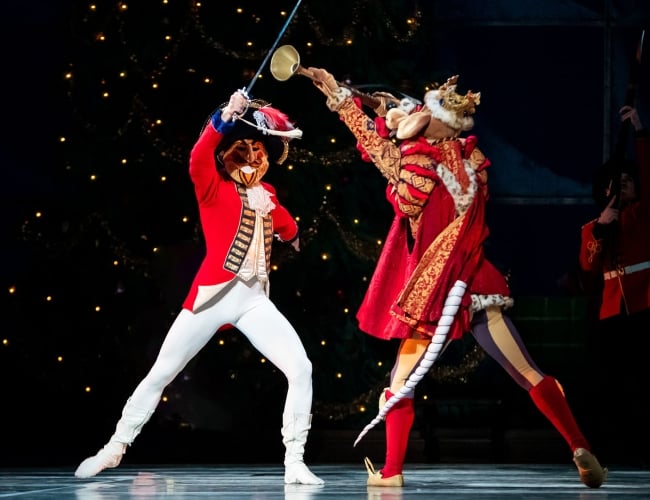 An image of two people fencing in costumes on stage.