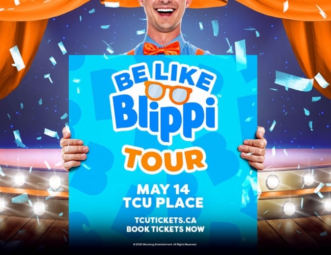 An image of a man on stage holding a blue sign. 