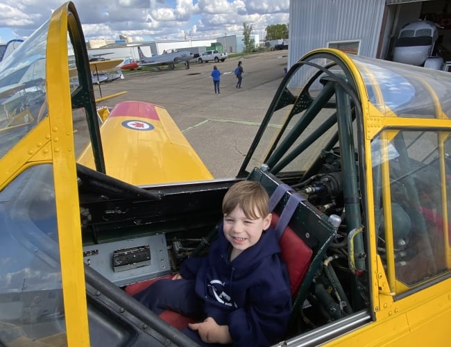 Young person seated at the flight controls of a World War II Aircraft