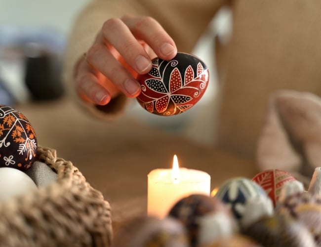 Female hand holding a finished pysanka egg above candle