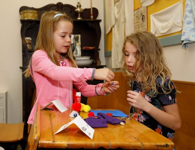 A young child is showing her craft to another child. 