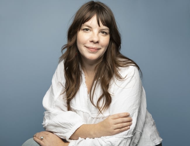 Headshot of Darby Sutherland on blue background