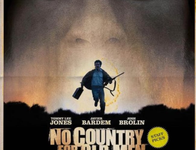 Image of a man with a gun and a suitcase running in the dessert and another mans face behind him, taking over the sky. 