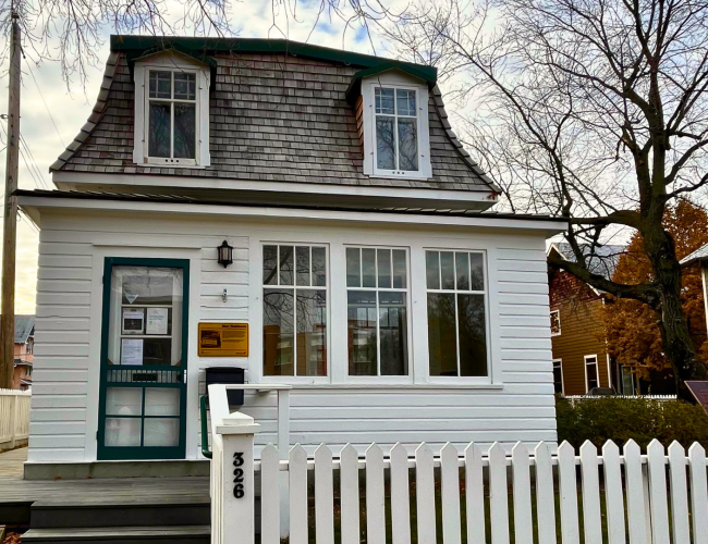 exterior of a historic home, white with green trim, a white picket fence 