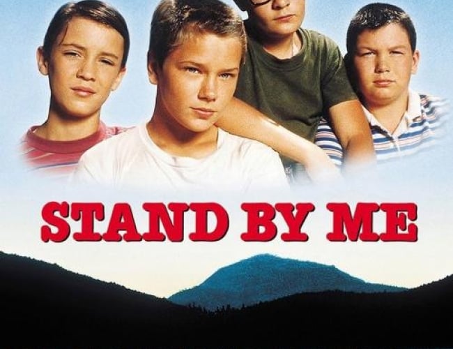 Image of four young boys and a lake with a mountain behind it. 
