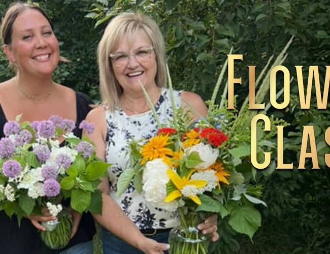 Two women stand outside at Black Fox Farm and Distillery holding flower arrangements after attending a flower class.