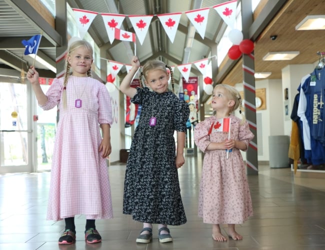 Three youth hold Canada flags.