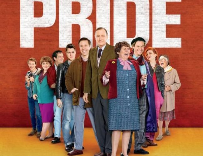 Image of ensemble cast from the movie PRIDE, standing one after the other, posing and smiling.