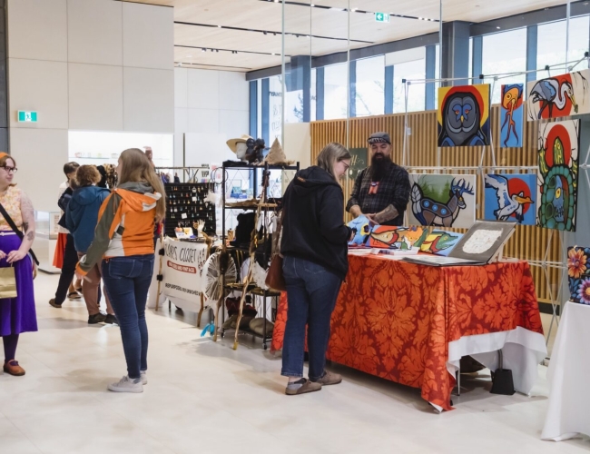 A photo of last year's Metis Market featuring shoppers browsing booths in the atrium of Remai Modern.