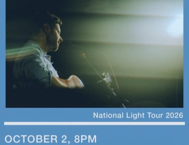Photo of Dan Mangan's side profile posing while playing with the lights blinding the audience outlook.