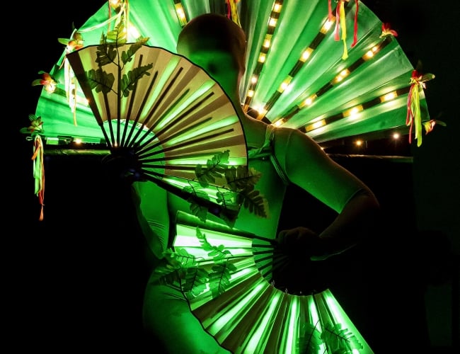 An alien dances with green fans