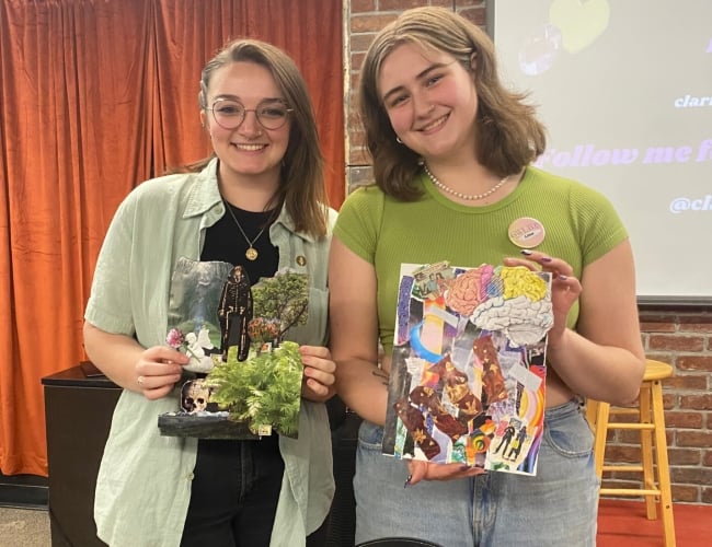 Two collage jam participants pose with their artworks crafting from collaging various materials. 