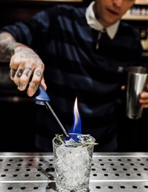 a bartender lights a cocktail on fire