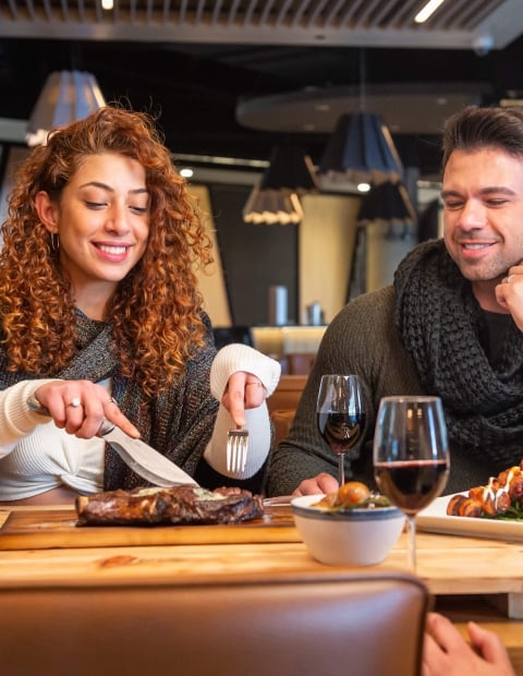 Couple sitting at a wooden table in a restaurant enjoying dinner
