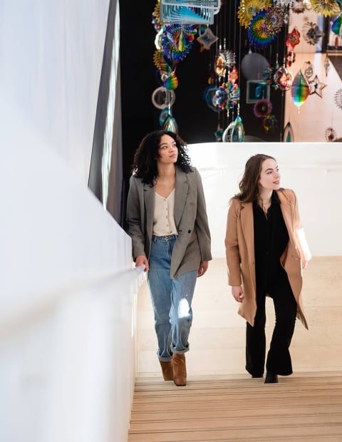 Two women walking up a staircase in an art gallery