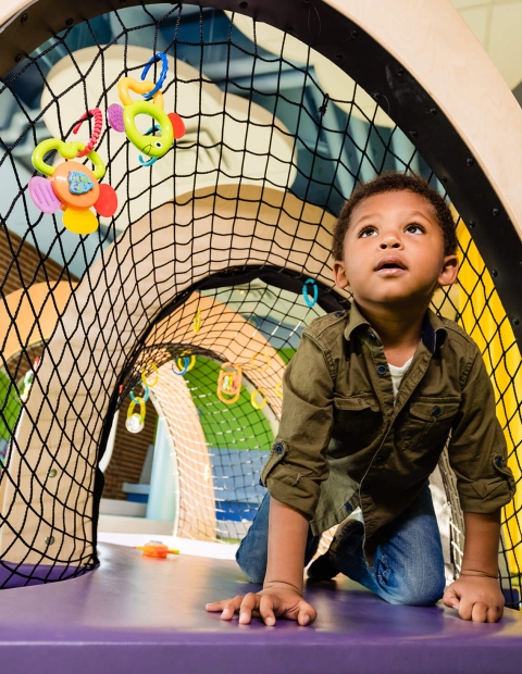 A child crawling through a colourful tunnel