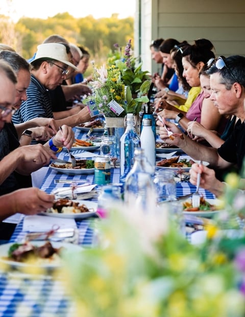 People sitting at an outdoor table with a blue and white checkered tablecloth
