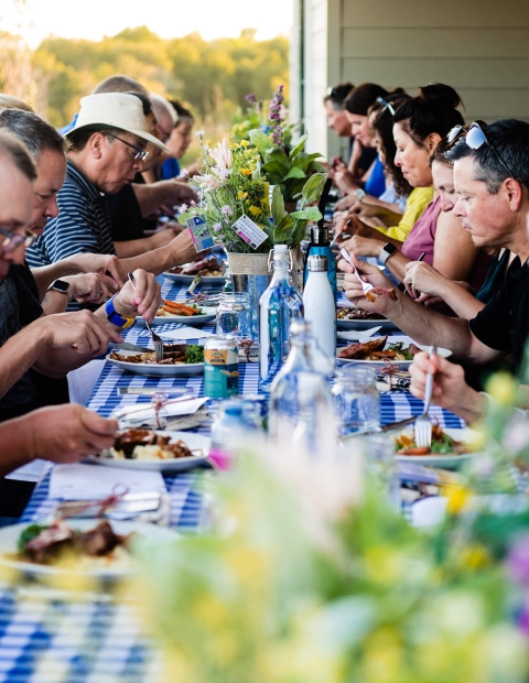 People sitting at an outdoor table with a blue and white checkered tablecloth